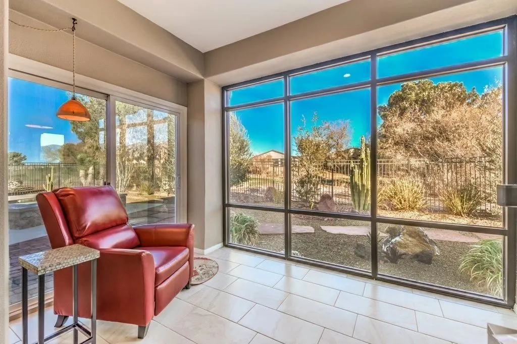 A sunroom with a red armchair and floor-to-ceiling windows onto a desert garden