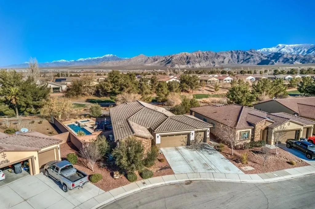Aerial view of a cul-de-sac of tile-roofed homes, snow on the peaks behind