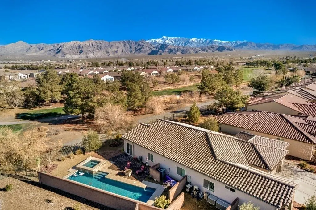 Aerial view of a tile-roofed home with a backyard pool and spa